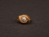 une bague en or avec un diamant au centre, sur un fond noir