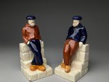 pair of ceramic figurines of two men sitting on a chair