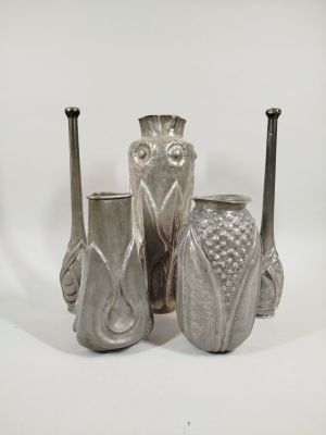 three silver vases sitting next to each other on a white surface