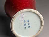 a red apple sitting next to a white vase with chinese writing on it