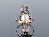 a gold and silver ring with a pearl in the center