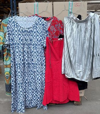 trois robes suspendues à un portant dans un entrepôt