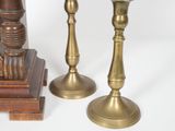 three brass candlesticks and a clock on a white background