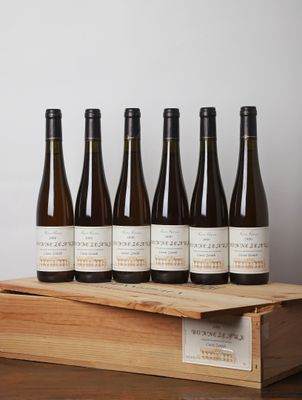 six bouteilles de vin sont posées dans une caisse en bois sur une table