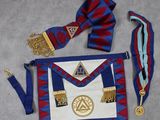 un tablier bleu et rouge orné d'une médaille d'or et d'un nœud papillon