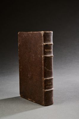 un vieux livre posé sur une table, à côté d'un verre