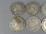 six different types of silver coins are shown on a gray surface