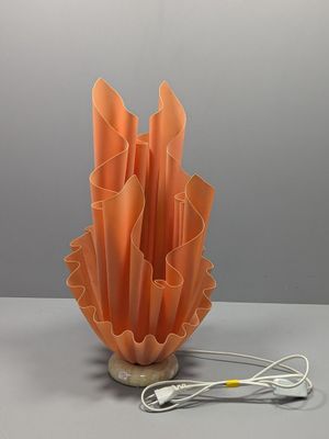 une lampe orange posée sur une table à côté d'un chargeur
