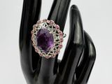 an image of a ring with a purple stone surrounded by pink and white stones
