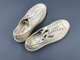 the white sneakers are on a gray surface with a yellow tag