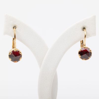 a pair of earrings with garnets on a white stand