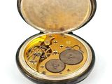 a pocket watch with a key in it on a white surface