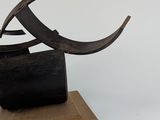 a metal sculpture of a bird on a wooden base