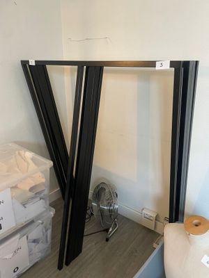 deux cadres noirs appuyés contre un mur blanc