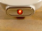 a white toilet with a red light on it
