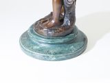 bronze statue of a boy holding a fish on a pedestal