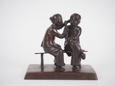 une statue en bronze représentant deux enfants assis sur un banc