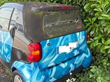 a small car that has been painted blue and has been parked on the side of the road