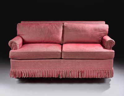 a pink couch with fringes on it in a dark room