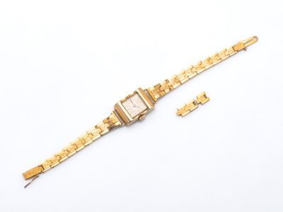 gros plan d'une montre en or sur une surface blanche