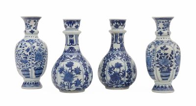 quatre vases bleus et blancs sont alignés sur un fond blanc