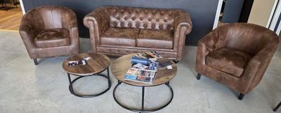 trois fauteuils en cuir marron et une table dans un salon
