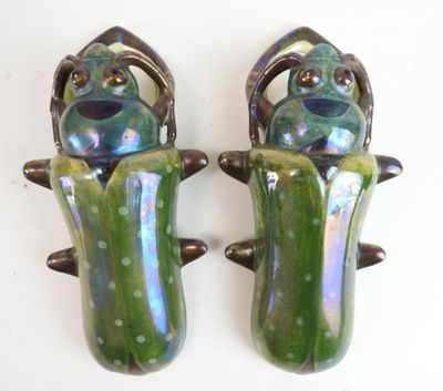 une paire de figurines de grenouilles vertes et violettes posées sur un fond blanc