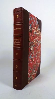 an old book with a red cover sitting on top of a white table