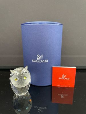 une figurine de chouette posée à côté d'une boîte de Swarovski