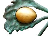 a gold egg sitting on top of a metal flower
