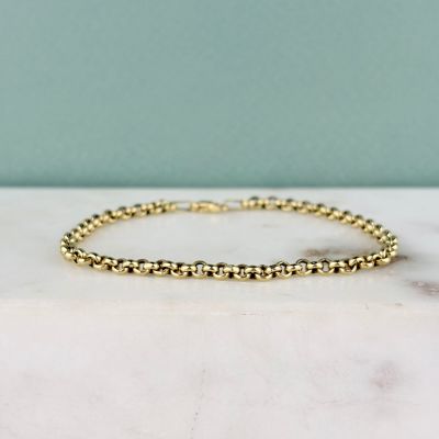 un bracelet orné de perles dorées posé sur une surface en marbre