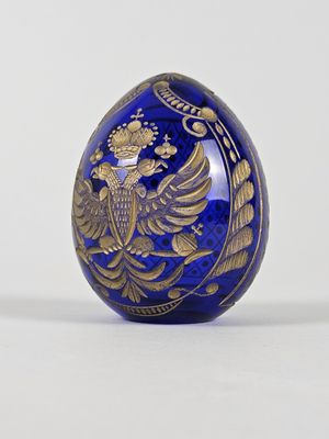 un œuf bleu et doré sur lequel est représenté un oiseau