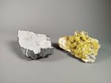 deux morceaux de minéral jaune et blanc sur une surface grise