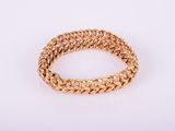 a close up of a gold bracelet on a white surface