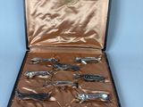 six silver spoons in a case on a table