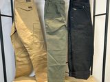 trois paires de pantalons pour homme suspendues à un portant dans une pièce