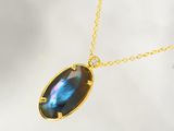 un gros plan d'un collier orné d'une pierre bleue sur une chaîne en or