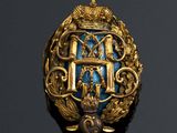 a close up of a gold and blue broochle on a black surface