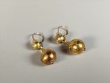 a pair of gold earrings on a white surface