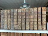 de nombreux livres anciens empilés sur une étagère dans une pièce