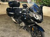 une moto noire garée sur un parking près d'une clôture