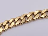 a close up of a gold chain bracelet on a white surface