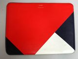 une housse d'ordinateur portable rouge, blanche et bleue posée sur une table