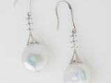 a pair of white pearl and diamond earrings on a white background