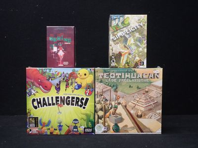 three board games sitting on top of each other on a black surface