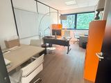 une pièce avec un bureau, des chaises, un fauteuil, une lampe et une grande fenêtre