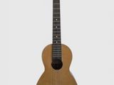 une image représentant une petite guitare en bois posée sur une surface blanche