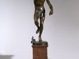 statue of a man on a pedestal in a room with a white wall