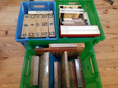 une boîte verte contenant des livres, posée sur un plancher en bois