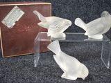 three glass birds sitting on a clear table